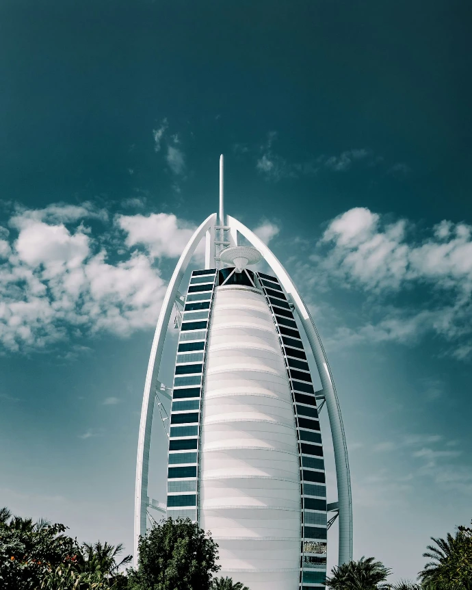 a tall building with a cloudy sky with Burj Al Arab in the background